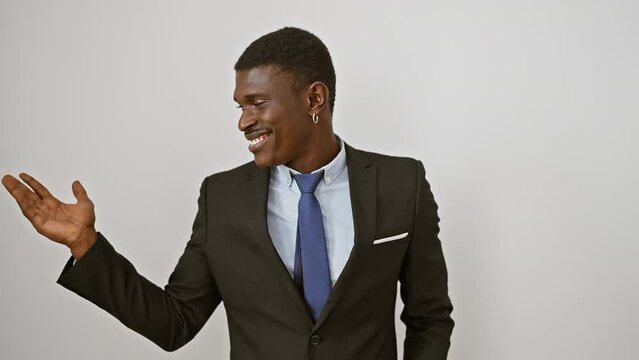 Handsome african american man, suit-clad and standing tall, cheerfully pointing and presenting with a palm gesture. smiling and looking directly at you from an isolated white background.