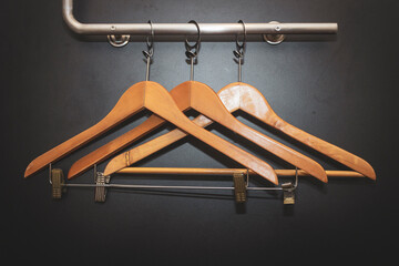 Three empty wooden clothes hangers with external flash without shirts or dress hanging on a...