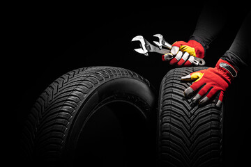 Car tire service and hands of mechanic holding new tyre and wrench on black background with copy...