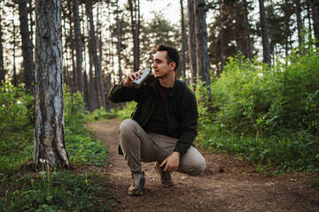 Naklejka na ściany i meble One caucasian male taking a break to drink water while hiking