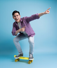 Photo of younf Asian man skating on blue background
