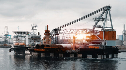 Wind Generators And Offshore Construction Crane Vessel With The Cargo Of Monopiles On Deck. Ship...