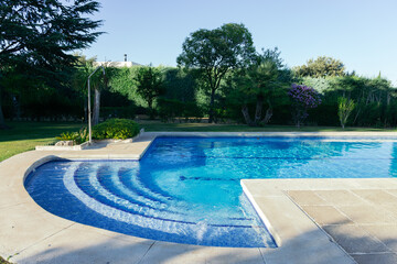 Private pool in a private garden surrounded by lawn, trees and a shower on a sunny summer...