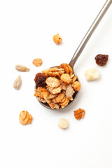 Muesli oat cereals with raisins, dried fruits and sunflower seeds in iron spoon on white background