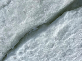 A deep dark crack in the ice floe. Diagonal line.