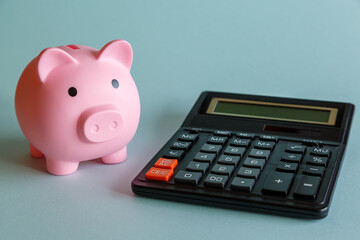 Piggy bank in the form of a pink pig and a calculator on a light background.