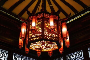Obraz premium a beautiful chinese lantern with bird and floral tree intricate designs from the ceiling light and illuminating the room.