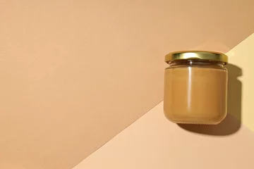  Peanut paste in a glass jar, on a light background. © Atlas