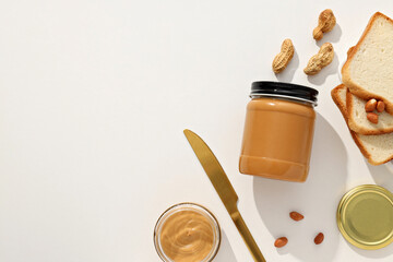 Peanut paste in a glass jar, on a light background.