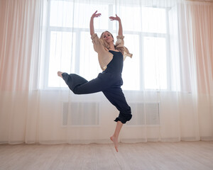 Caucasian woman dances contemporary in ballet class. Dancer in a jump. 