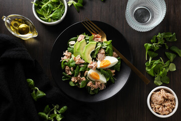 Salad with tuna on a dark table with a fork.