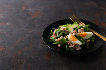 Salad with tuna on a dark table with a fork.