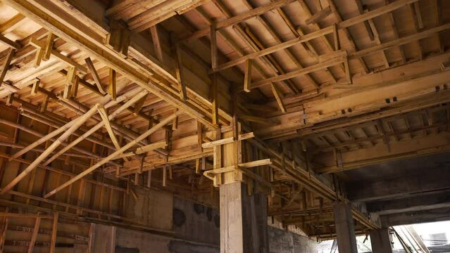 Scaffolding at construction site. Wooden roof framework of unfinished building. Works processed with ceiling in new apartment building.