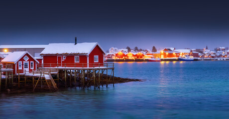 Scenic night lights of Lofoten islands, Norway, Reine and red houses in fishing village on a sea shore.
