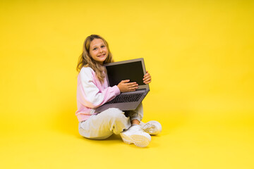 Positive kid sit with laptop read homework wear casual style cloth isolated over yellow background