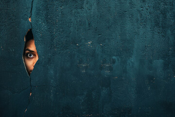 A person peeking through a crack on a dark color wall - obrazy, fototapety, plakaty