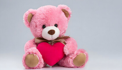 Seated pink teddy bear with heart on white background. Soft cute fluffy plush toy. Valentine stuffed animal.