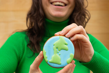 Earth Day concept. Gingerbread in the shape of a planet in the hands of a woman. - 782919393