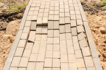 Perennial tiles on a pedestrian path in the yard after repair. Incorrect performance of tile laying...
