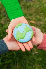 Earth Day concept. Hands hold gingerbread in the shape of the Earth. Care for the environment.