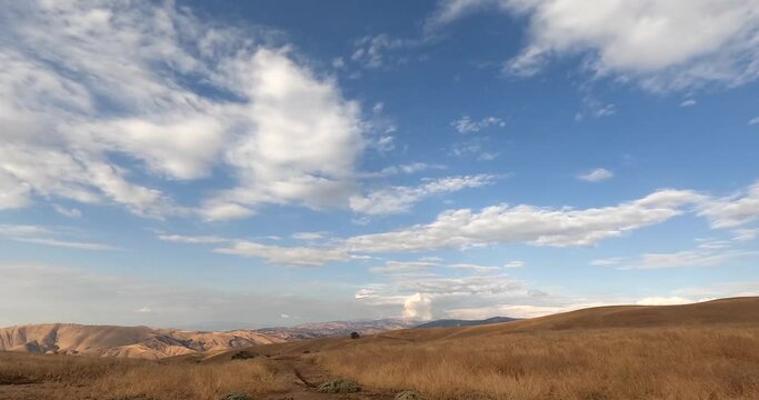 Time lapse footage of clouds moving on blue sky over brown grass fields in California