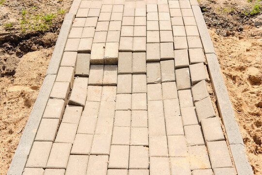Perennial tiles on a pedestrian path in the yard after repair. Incorrect performance of tile laying work. Improvement of cities