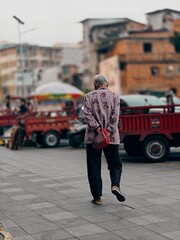 Nanning, China, March 31, 2024: Asian grandmother walking down the city street, elderly Chinese...