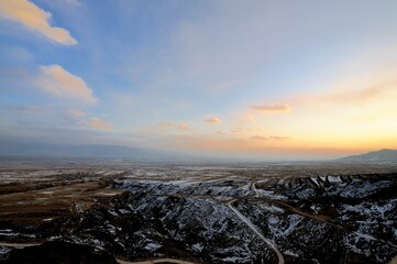 Aerial shot of a landscape covered in snow under the clouds