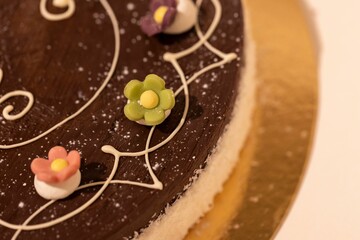 Closeup of a chocolate cake decorated with flowers on a tray with a blurry background