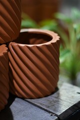 Vertical selective focus of clay terracotta pots on a wooden table with plants in the background