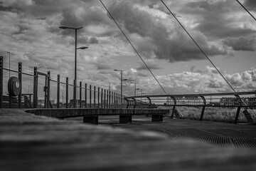Grayscale shot of a caged bridge under a cloudy sky.