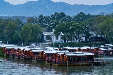 Naklejka premium Snow covered roofs of Chinese pavilions against a beautiful landscape with leafy trees