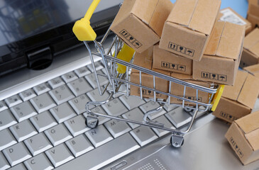 Close-up shopping cart and carton boxes on laptop computer keyboard. 