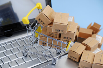 Shopping cart, and shipping carton boxes on laptop computer keyboard. Online shopping and selling concept.	