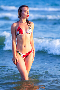 Pretty woman in bikini swimsuit is posing on a sea beach