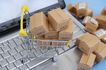 Close up of shopping cart, and many carton boxes on computer keyboard. 