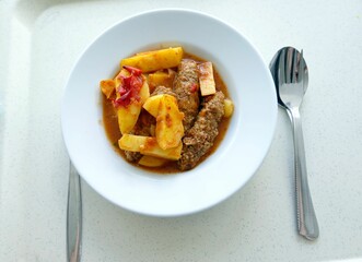 Closeup of Meatballs with tomato and potatoes on a white plate