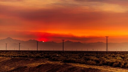 Beautiful view of a countryside landscape with power lines at sunset with crimson sky