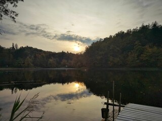 Beautiful view of a lake surrounded by autumn trees in a forest during sunrise