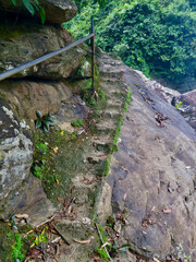 Stone stairs in the mountains. Staircase carved in stone in the jungle. Steps carved in stone lead up. Stone staircase and iron railing.