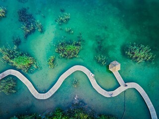 Drone shot of turquoise water and a wooden bridge at Park Grodek in Jaworzno, Poland