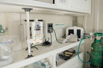 Green medical oxygen cylinder with other hospital equipment inside an Ambulance