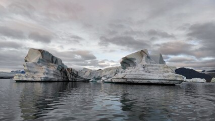 Floating icebergs in the water against a cloudy sky
