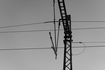 Low angle grayscale shot of a steel tower with electricity lines