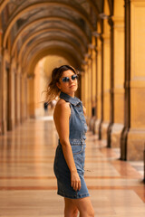 Immersed in the enchanting ambiance of Bologna's renowned porticoes, a young woman elegantly poses...