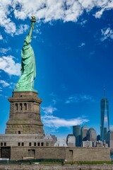 Vertical shot of the historic Statue of Liberty and the skyline in the background