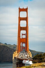 Vertical shot of the historic Golden Gate Bridge with cars on a bright day