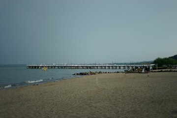 Naklejka premium Sea waves splashing over the shore with a pier in the background