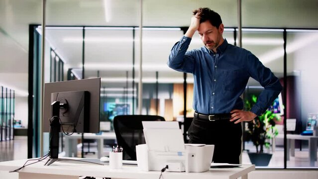Irritated Businessman Looking At Paper Stuck In Printer