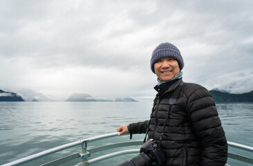 Tourist carrying a big camera and posing for phones. Boat cruising Resurrection Bay, Kenai Fjords, Seward, Alaska.